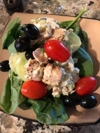 Homemade chicken salad and cucumber salad on a bed of spinach