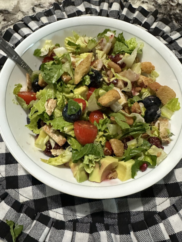 Dinner is grilled chicken salad. It has Romaine, blueberries, kiwi, pomegranate, grape tomatoes, cro